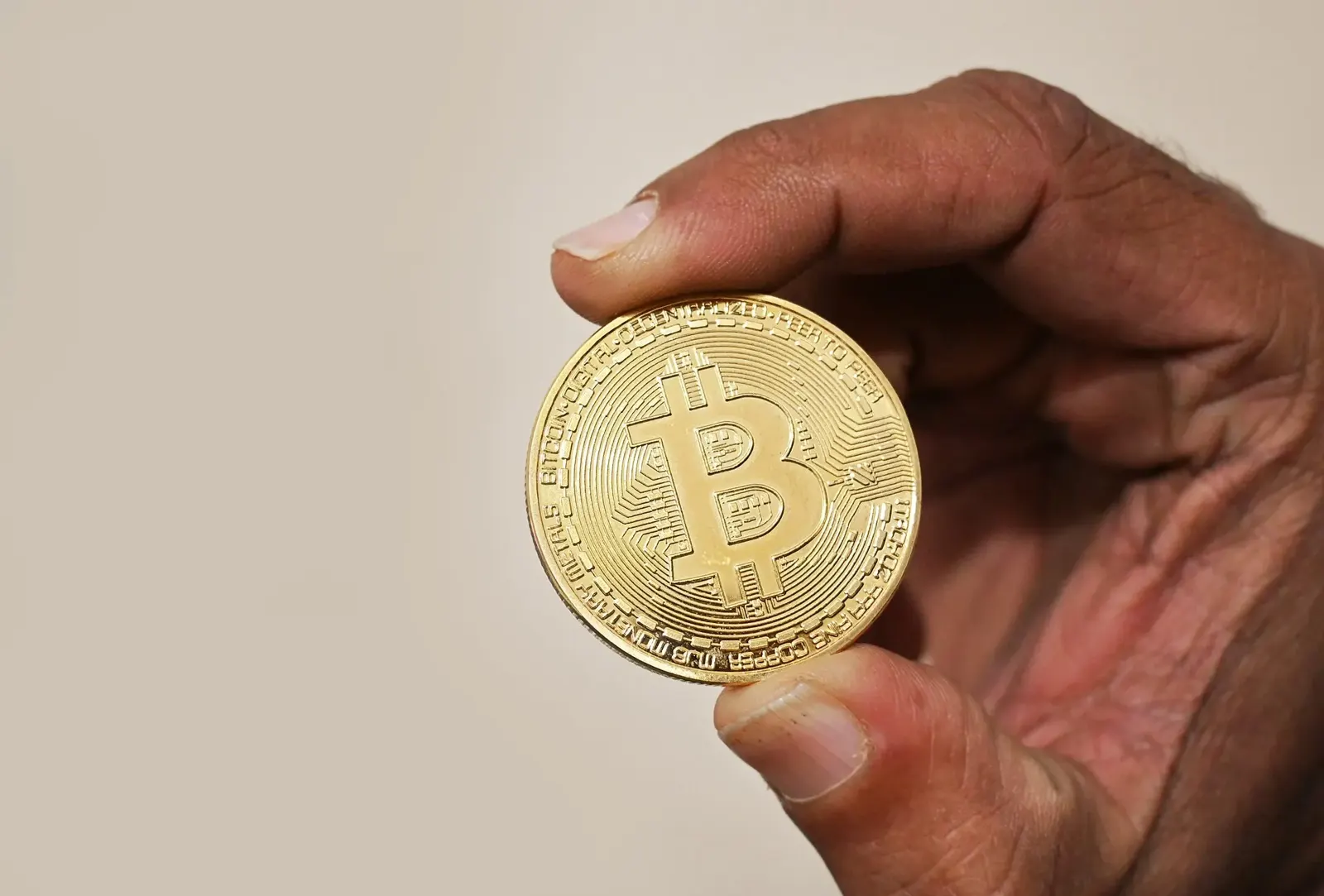 Gambar: Satheesh Sankaran / Wikimedia Commons (CC BY 2.0) Tangan memegang syiling Bitcoin berwarna emas
