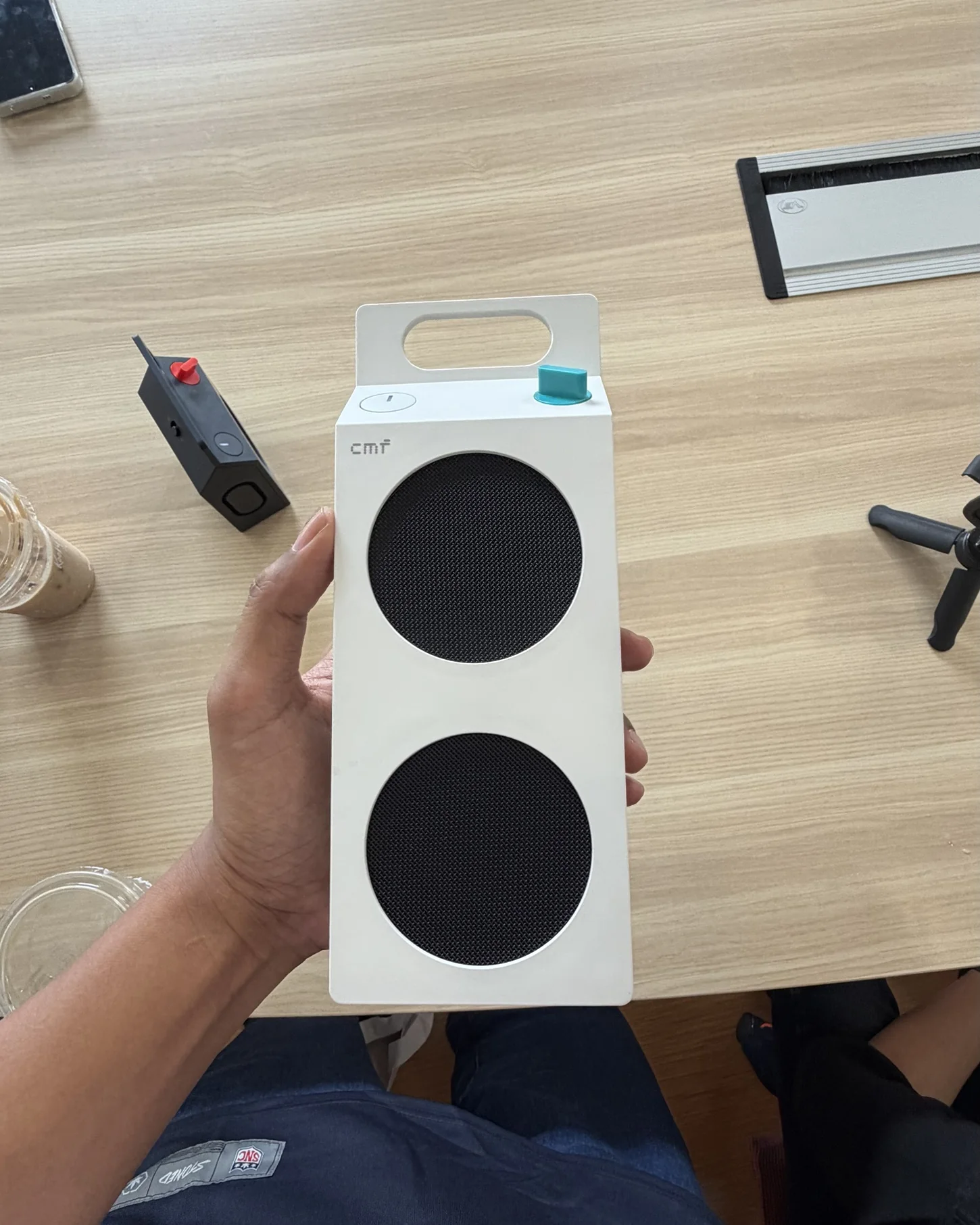 Tangan aku memegang CMF Speaker M warna putih dengan dua grill speaker dan knob turquoise