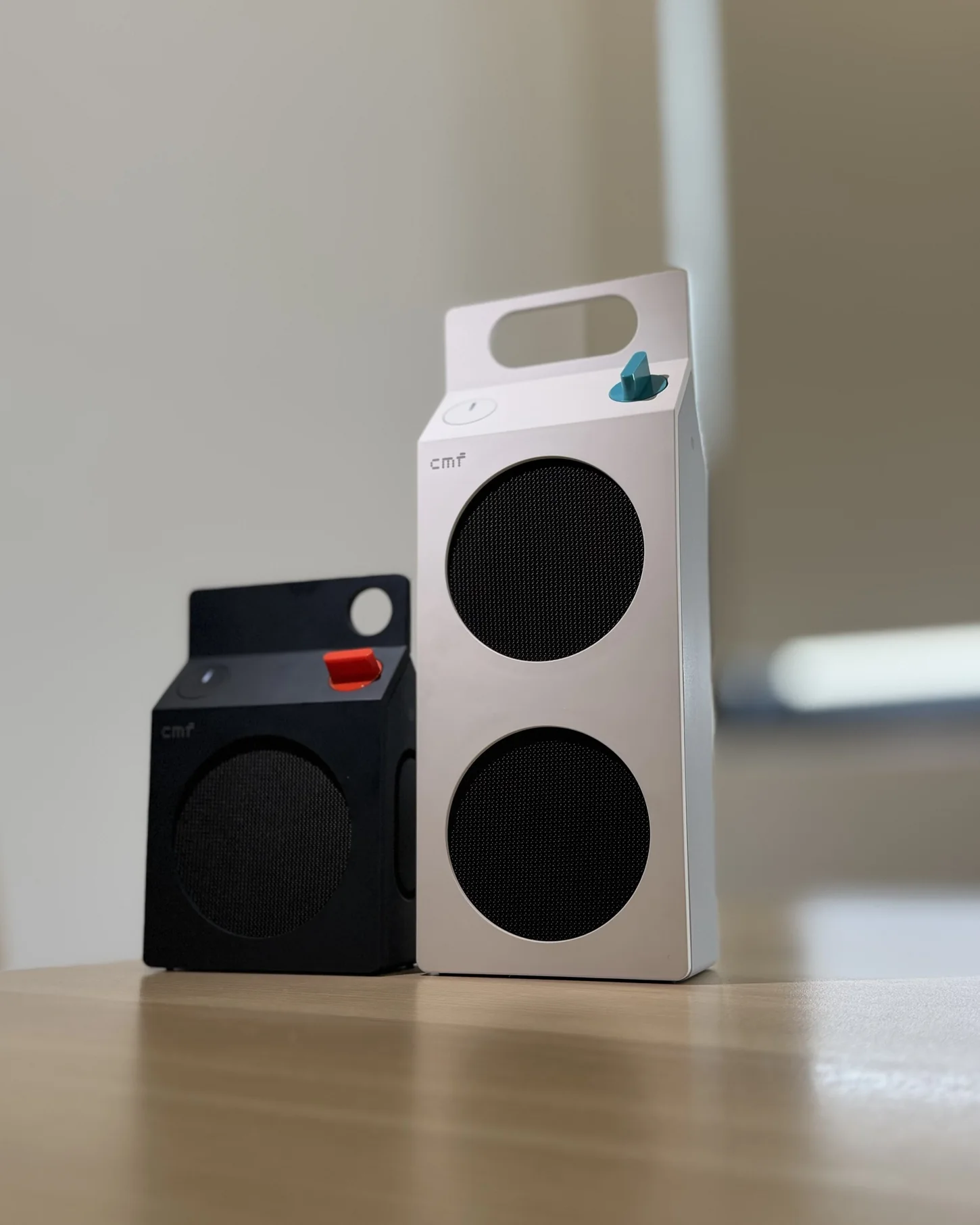 CMF Speaker S warna Dark Grey di sebelah CMF Speaker M warna putih di atas meja