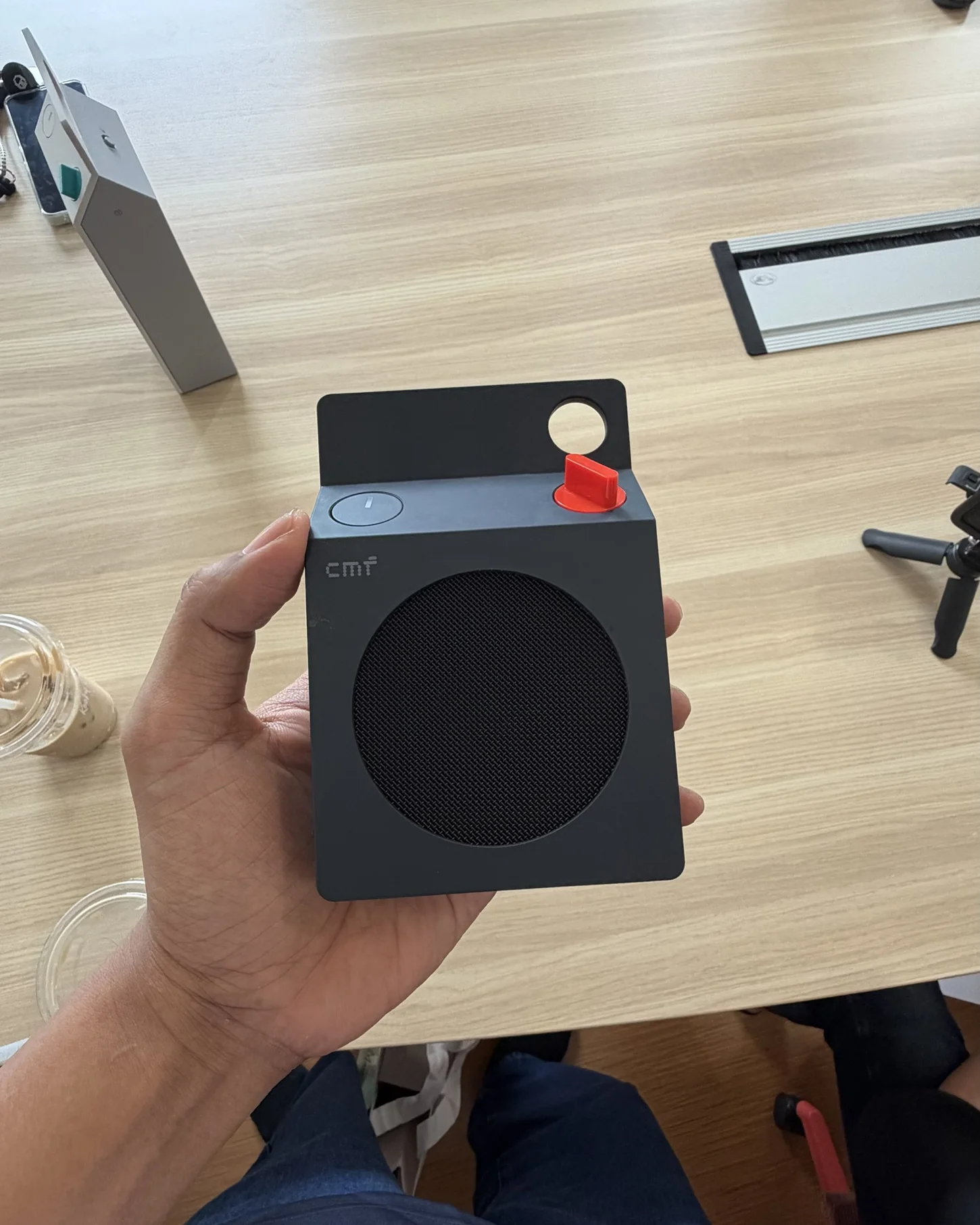 Tangan aku memegang CMF Speaker S warna Dark Grey dengan knob merah