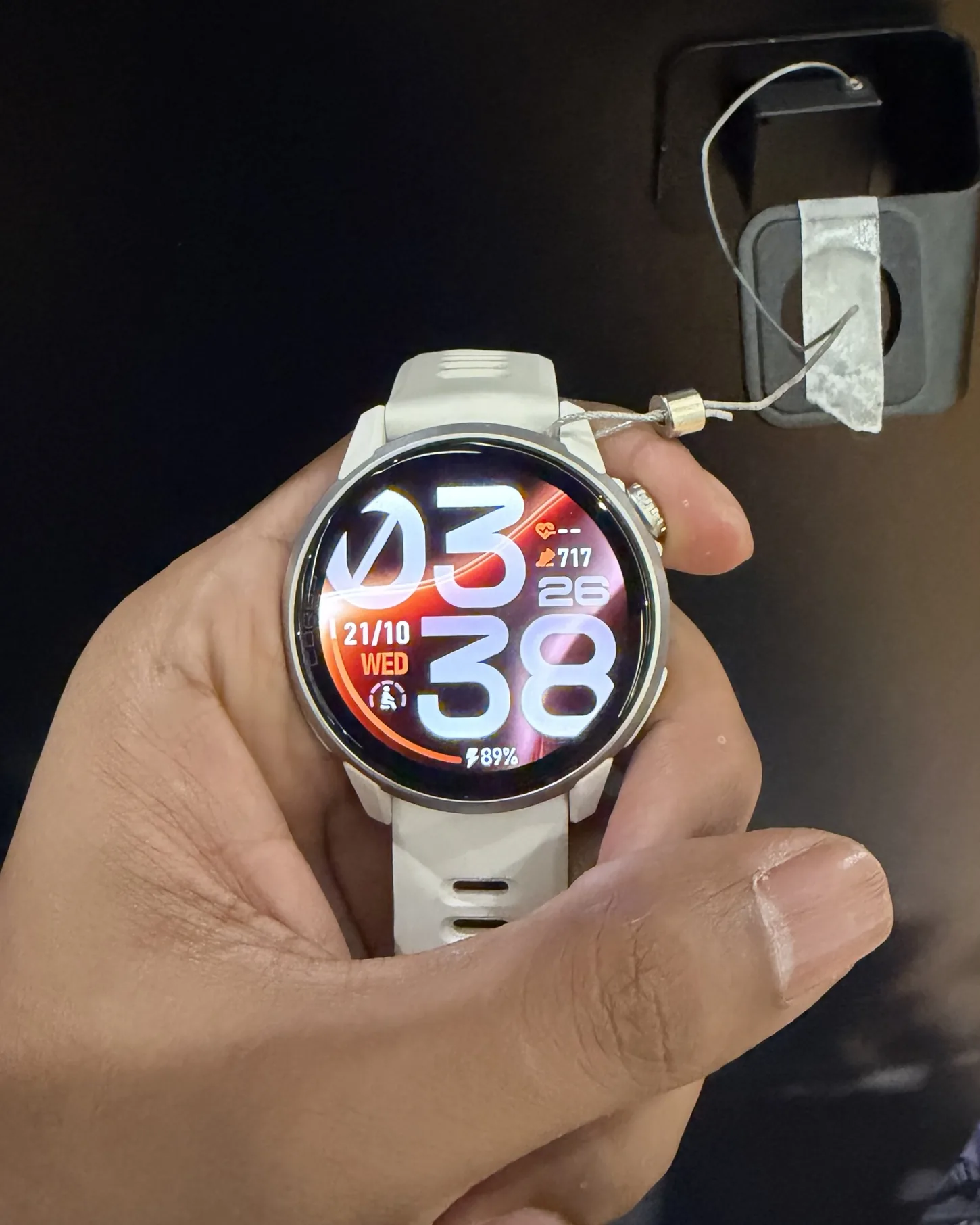 Tangan memegang COROS PACE 4 Pro putih dengan skrin AMOLED terang menunjukkan masa