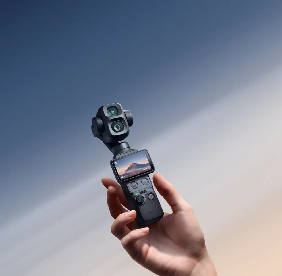 Hand holding the black DJI Osmo Pocket 4P against a soft blue background