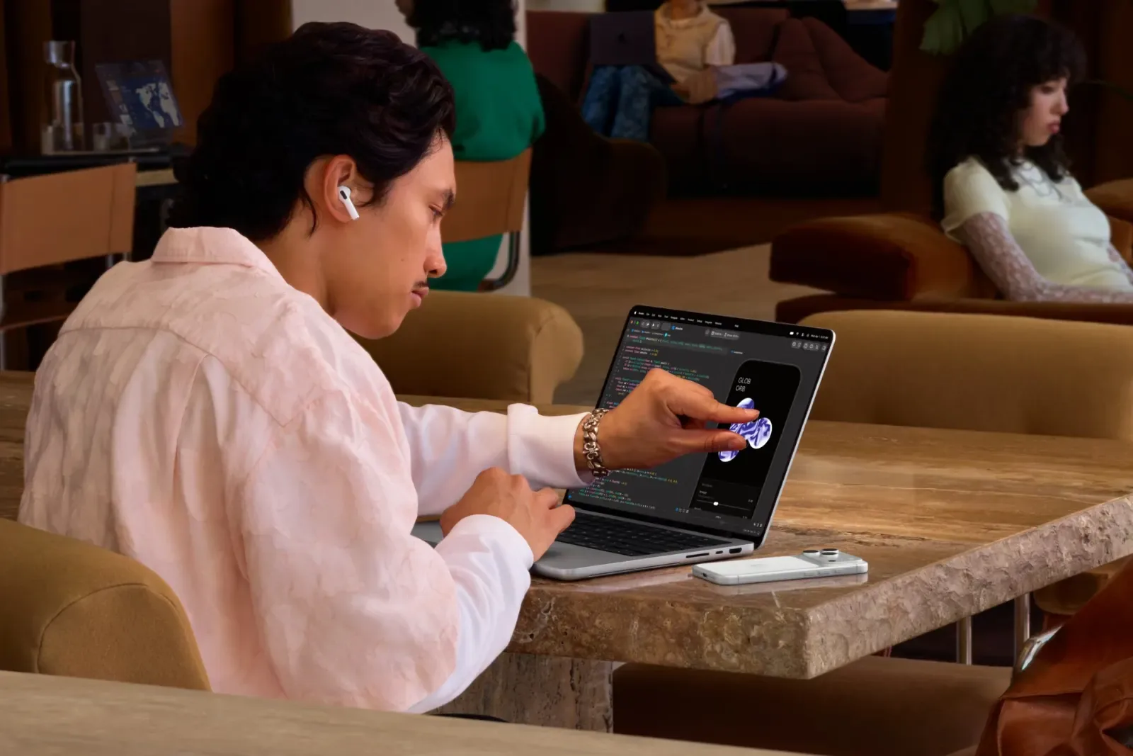 Gambar: Apple Pengguna duduk di meja menyentuh skrin MacBook Pro PROLED XDR