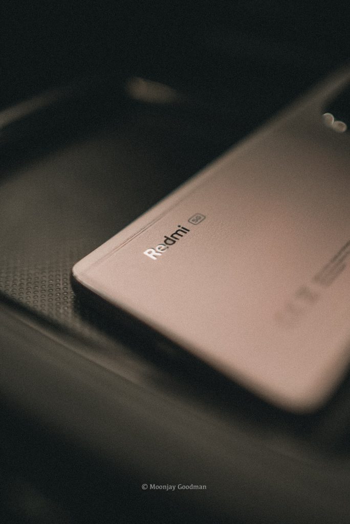 Redmi 5G logo on the back of the Redmi Note 14 Pro+ in low light