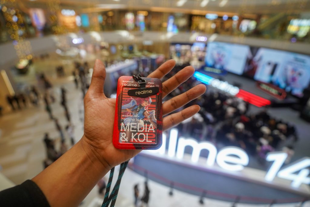 Holding a realme 14 Series Media and KOL pass above the launch stage